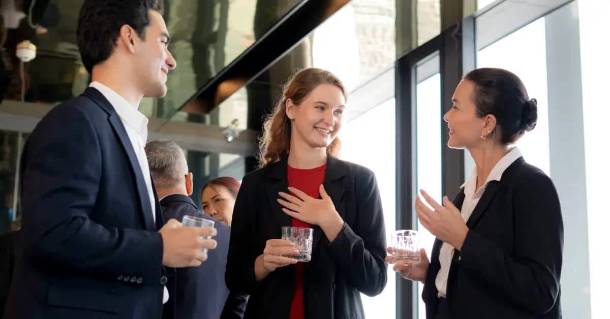 Colleagues at an in-person meeting standing in a circle chatting