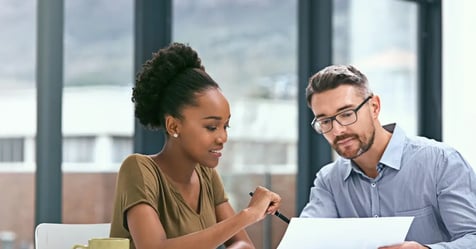 Colleagues in the office discussing travel tools for Executive Assistants