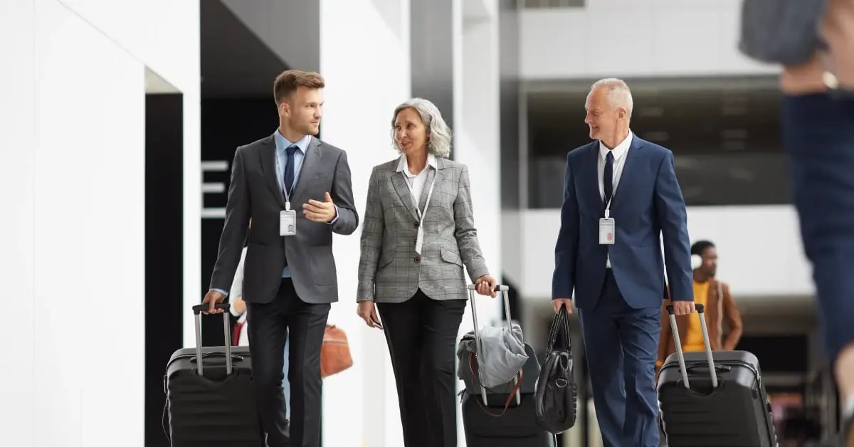 Colleagues traveling for business pulling suitcases in an airport