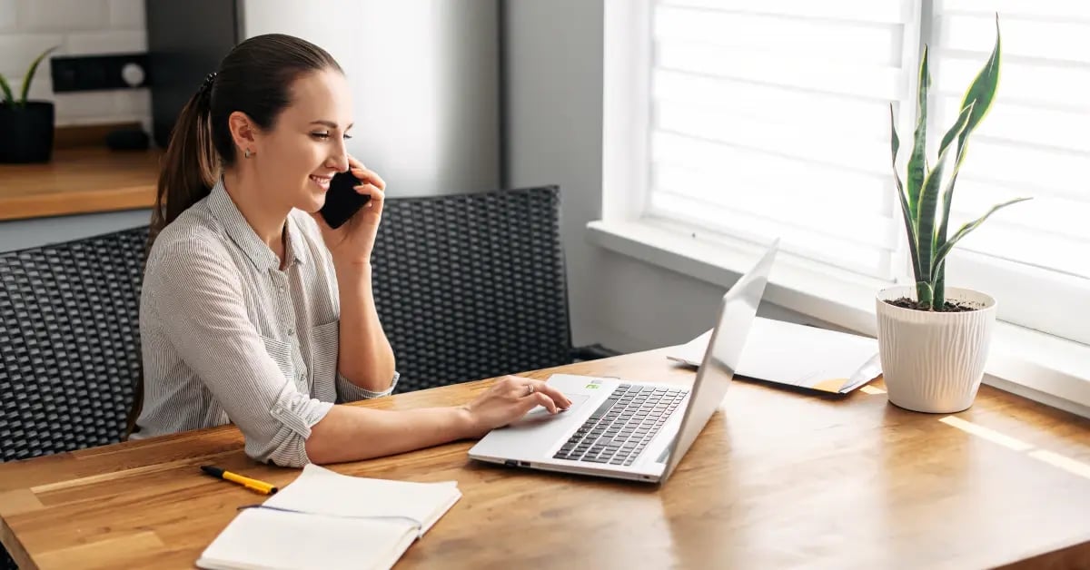 EA working on her laptop and talking on phone to create a contingency plan for a in-person meeting