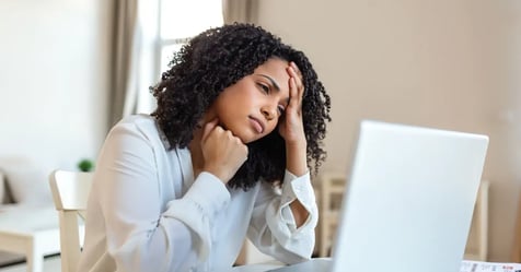 Executive Assistant burnout behind her desk at work, holding her head in confusion