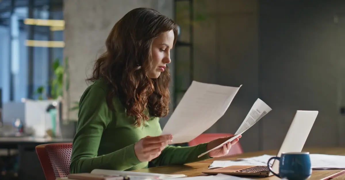 Executive Assistant holding paperwork to review to reduce in-person meeting costs