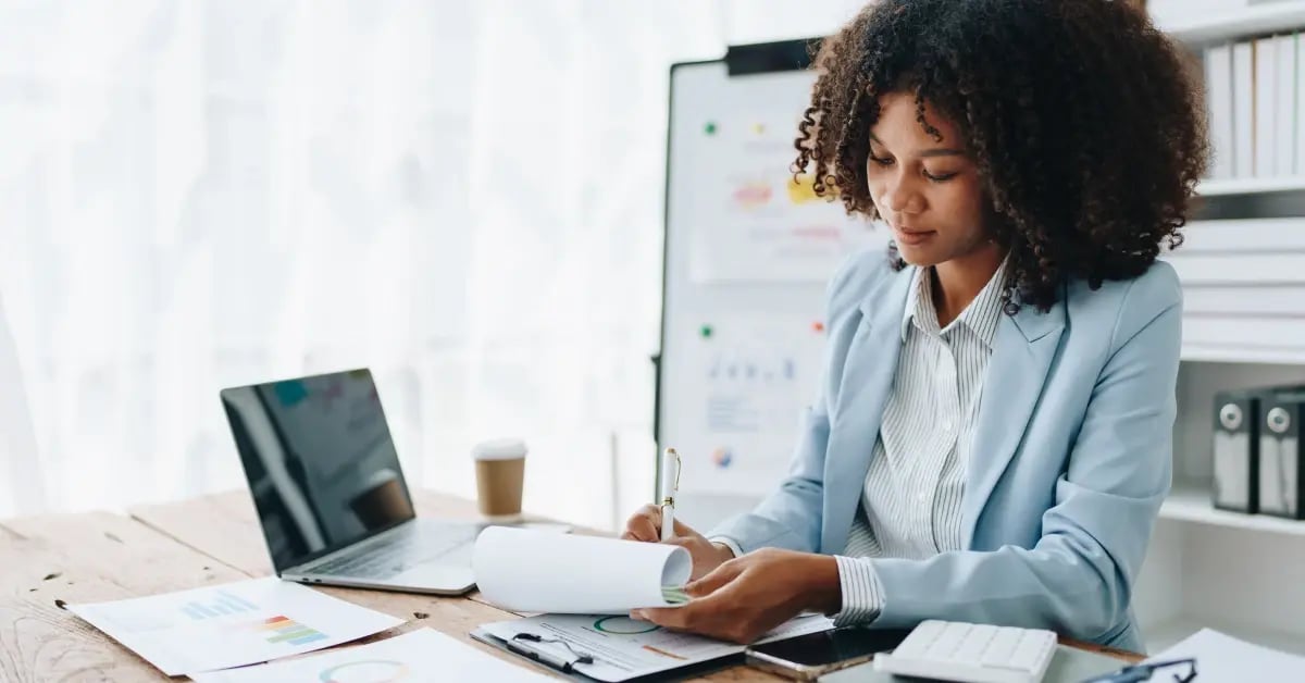 Executive Assistant planning an in-person meeting at her desk in the office while following a travel policy