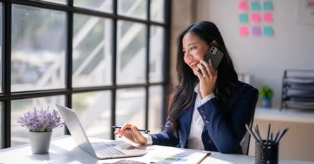 Executive Assistant talking on the phone and working on the laptop on meeting planning trends