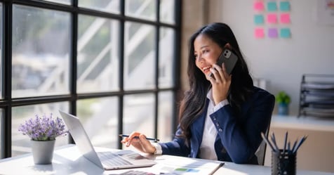 Executive Assistant talking on the phone and working on the laptop on meeting planning trends