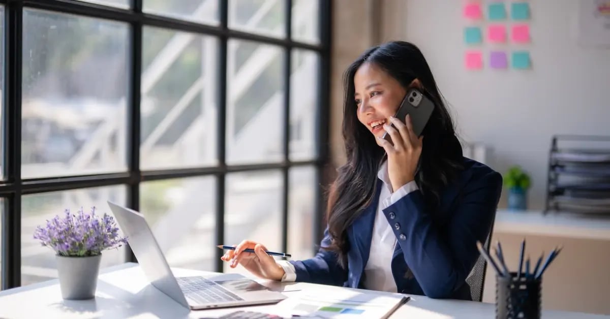 Executive Assistant talking on the phone and working on the laptop on meeting planning trends