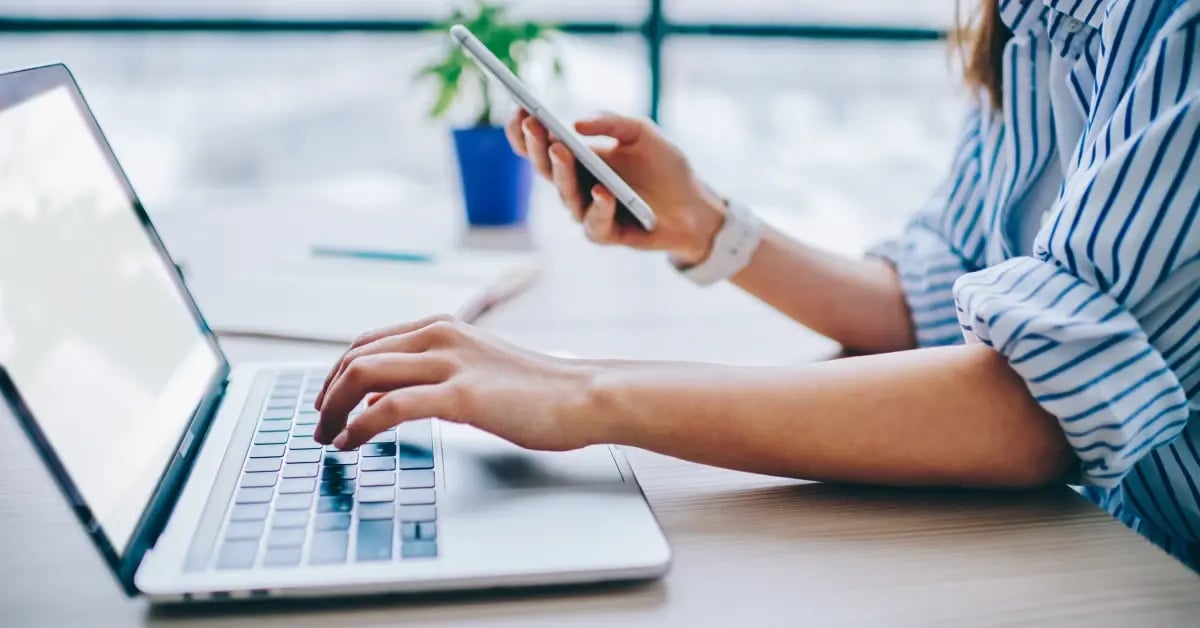 Executive Assistant using AI tools on her laptop and phone at the office