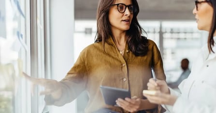 Executive Assistant utilizing communication skills while showing a colleague something work-related in the office