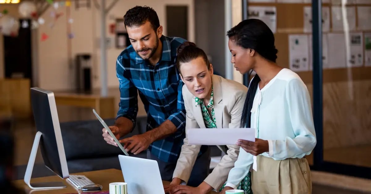 Executive Assistants in an office in front of a computer discussing in-person meeting budgets