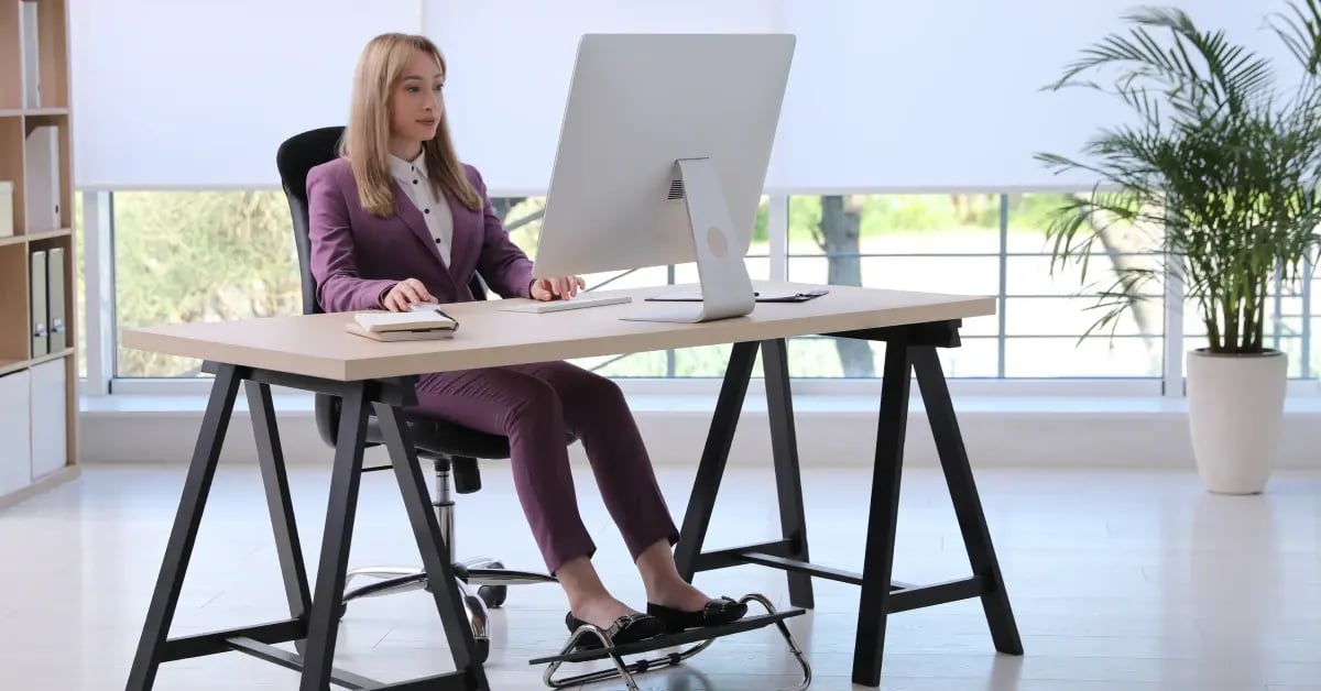 Female Executive Assistant sitting at her desk using a balance board