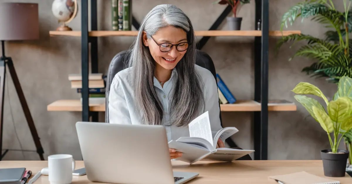 Older female Executive Assistant in her office, flipping through a book