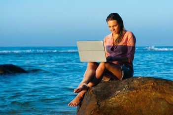 A woman working remotely at the beach