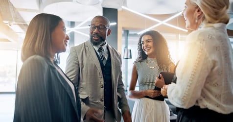 Team at an in-person meeting chatting while Executive Assistant pulls post-meeting communications