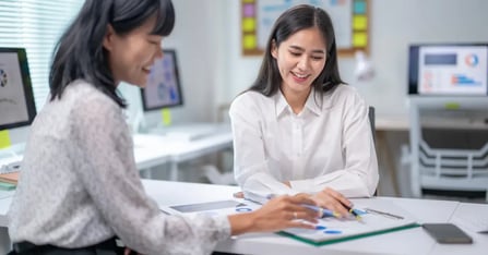 Travel Manager and Executive Assistant working together on in-person meetings in the office