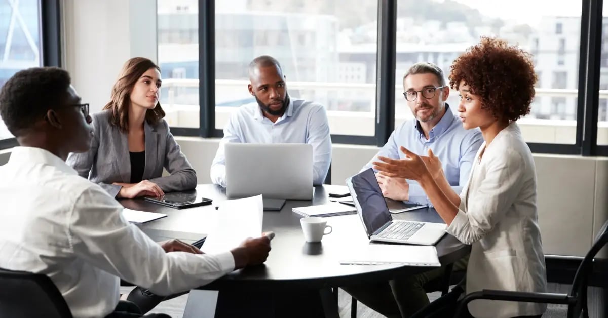 Travel Manager in a small meeting talking about in-person meeting benefits