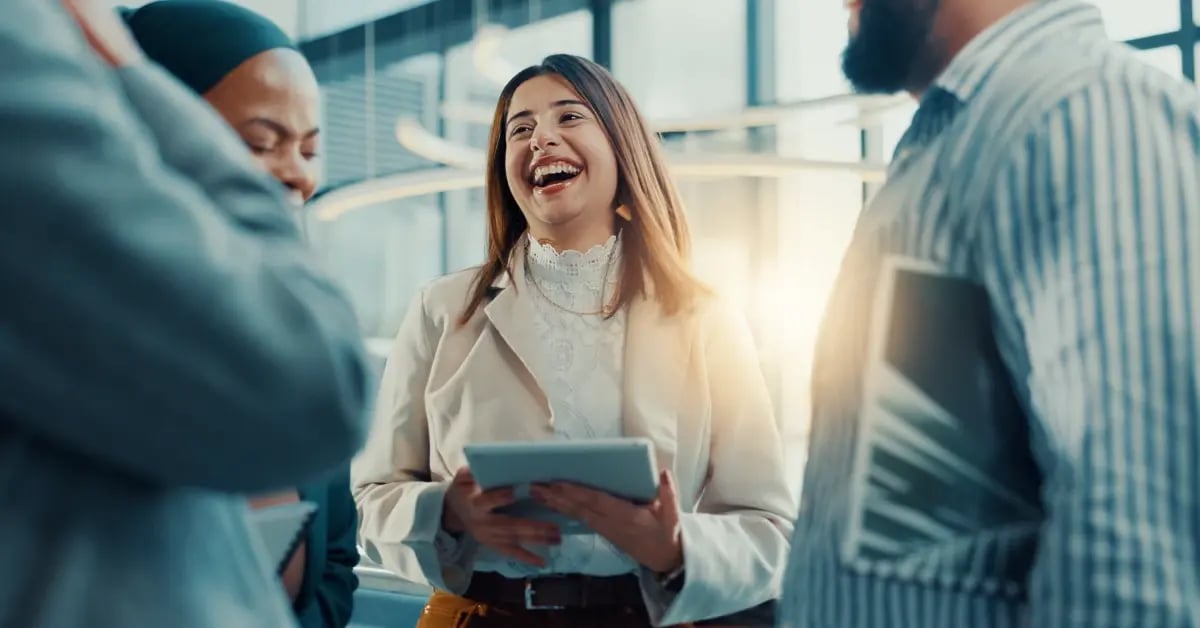 Travel Manager with tablet in hand connecting with her team at an in-person meeting