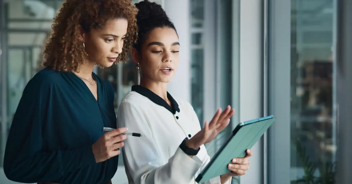 Two travel assistants standing and talking about travel budgets on a notepad