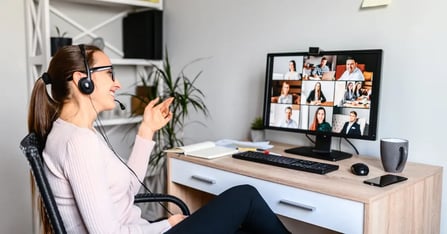 Woman working remotely with headphones on looking at her virtual meeting