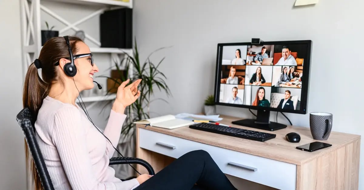 Woman working remotely with headphones on looking at her virtual meeting
