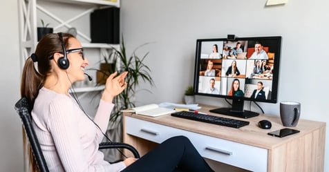 Woman working remotely with headphones on looking at her virtual meeting